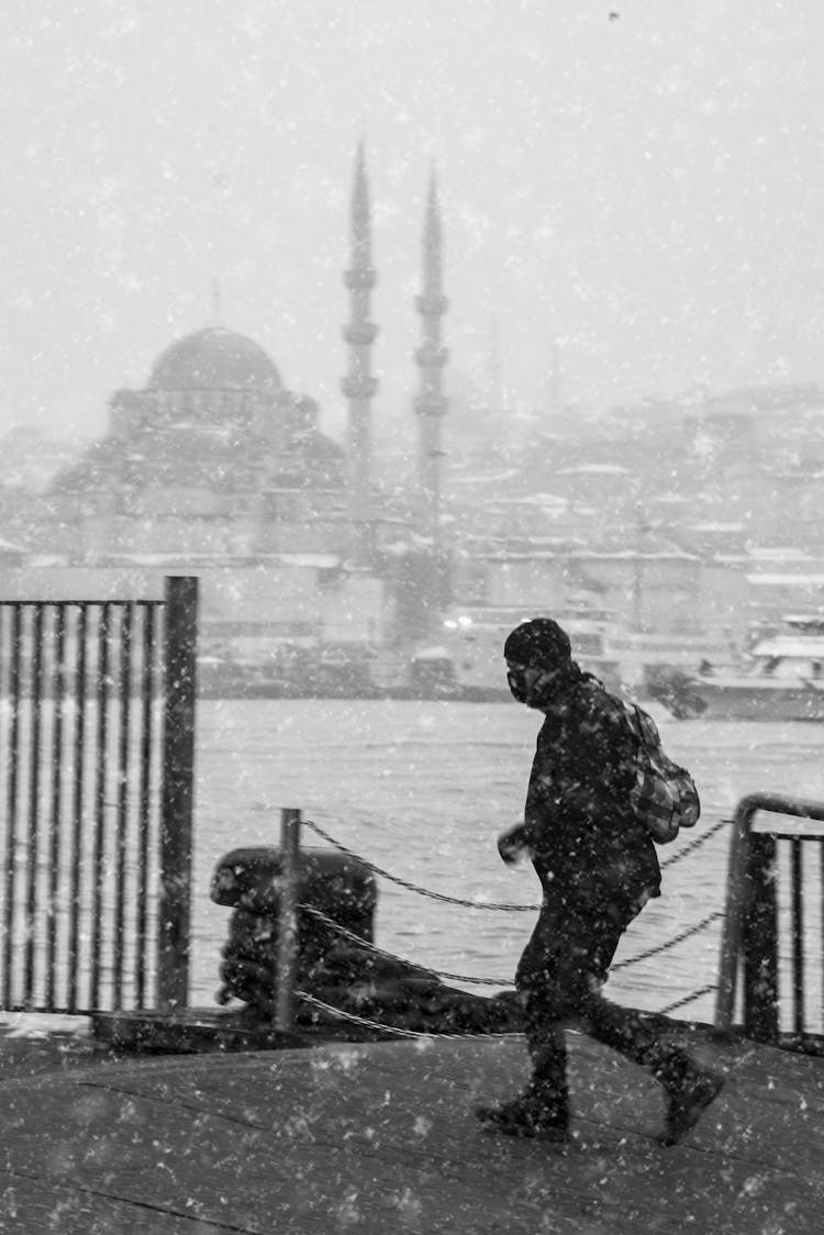 Man Walking On Pier In Snow 