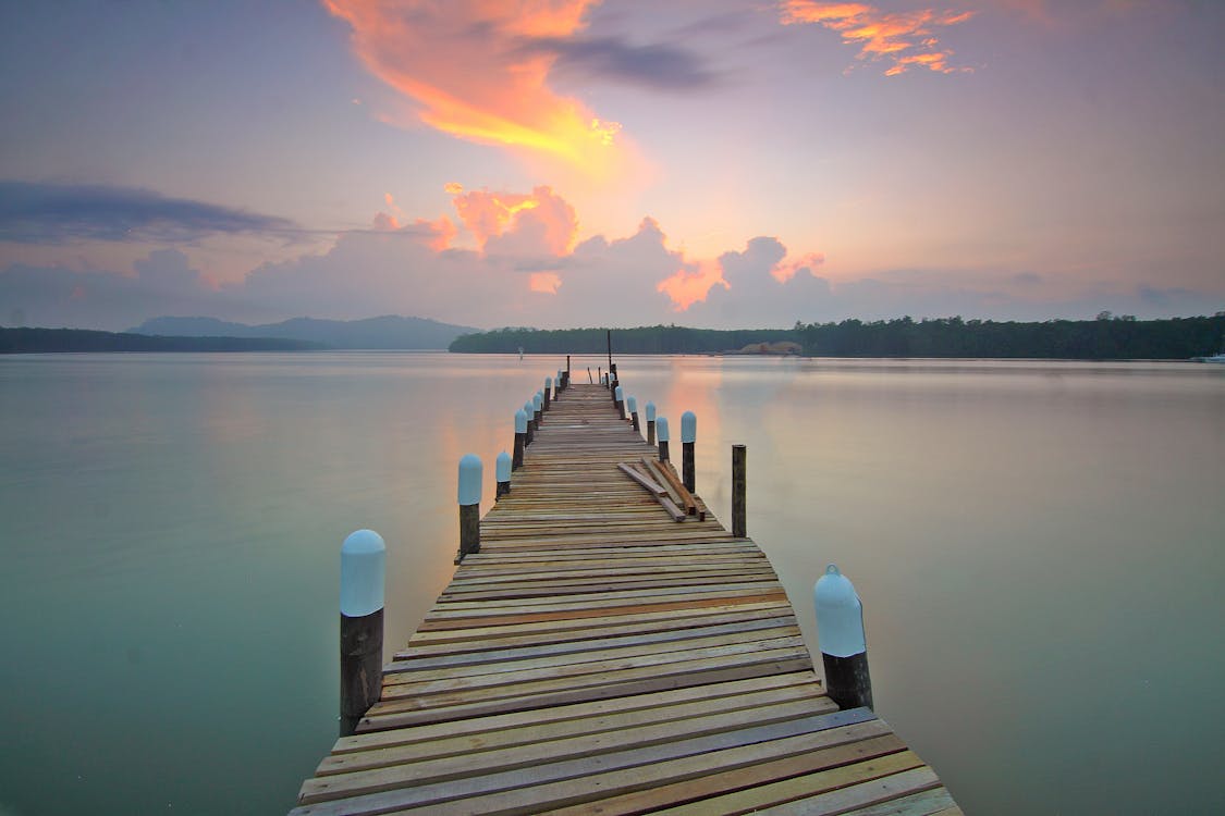 Brown Wooden Footbridge on Body of Water during Sunrise