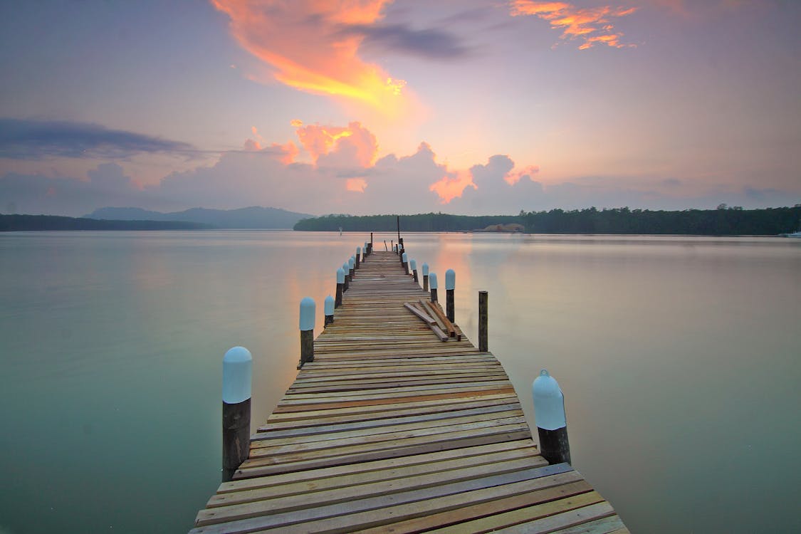 Free Brown Wooden Footbridge on Body of Water during Sunrise Stock Photo