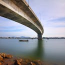 一座风景如画的现代桥梁横跨在宁静的河流上，桥下有一艘小船，凸显了建筑设计与宁静环境的和谐