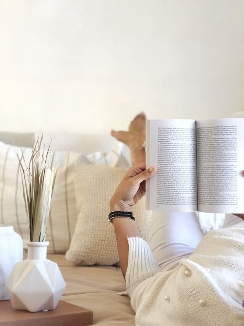 Woman Lying on Couch Reading Book