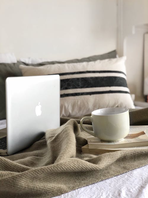 Latptop, Coffee Cup and Book on Bed