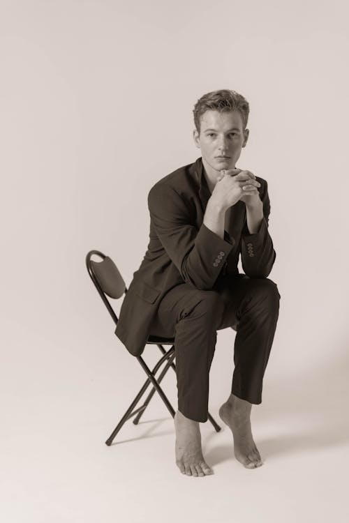 Model Man Sitting in Chair Barefoot in Mens Suit