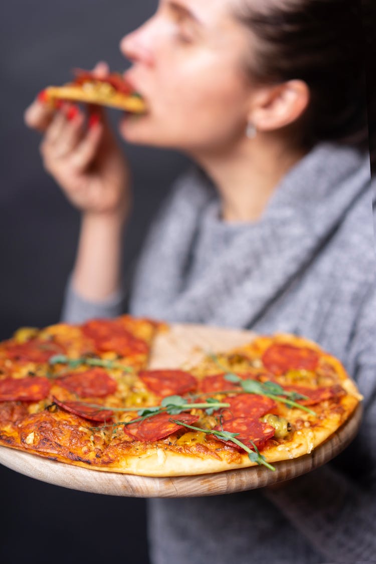 Woman Holding And Eating A Pizza