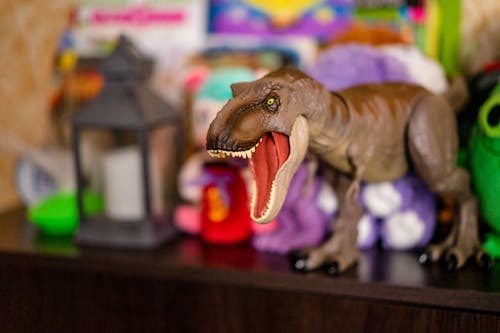 Brown Dinosaur Figurine on Brown Wooden Table