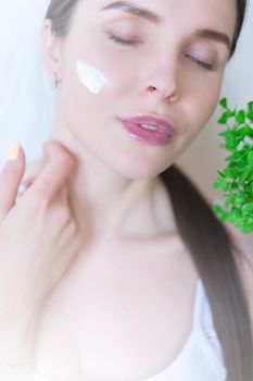 Close-up portrait of a woman applying skincare cream with closed eyes, blending beauty and tranquility.