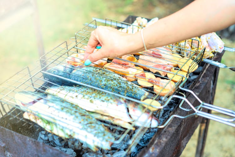 Woman Grilling Fish And Meat 