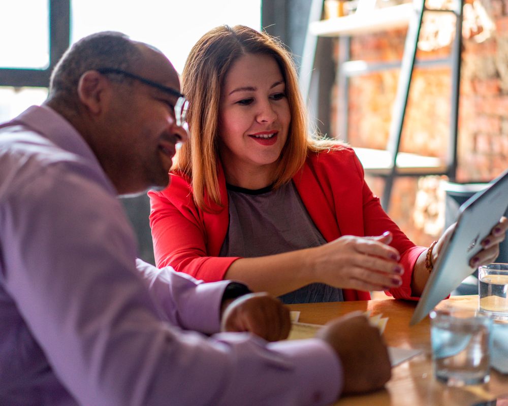 Two professionals reviewing customer data on a tablet in a modern office