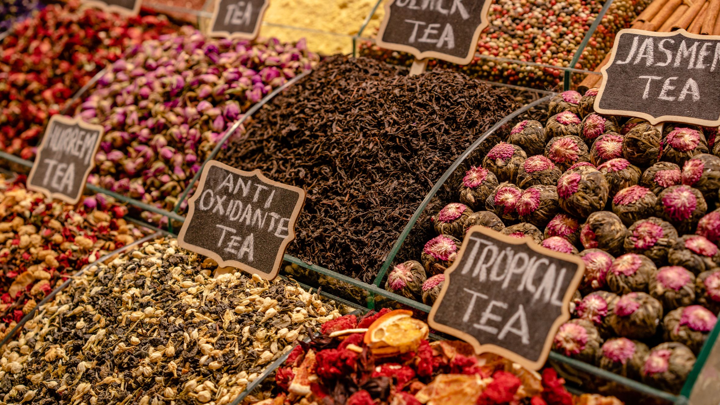 A vibrant display of various teas at a market stall, highlighting diverse flavors and colors.