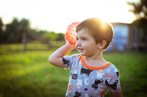 A Boy in Gray Printed Shirt Holding a Ball
