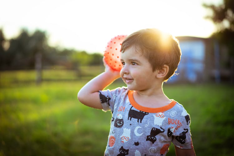 A Boy In Gray Printed Shirt Holding A Ball