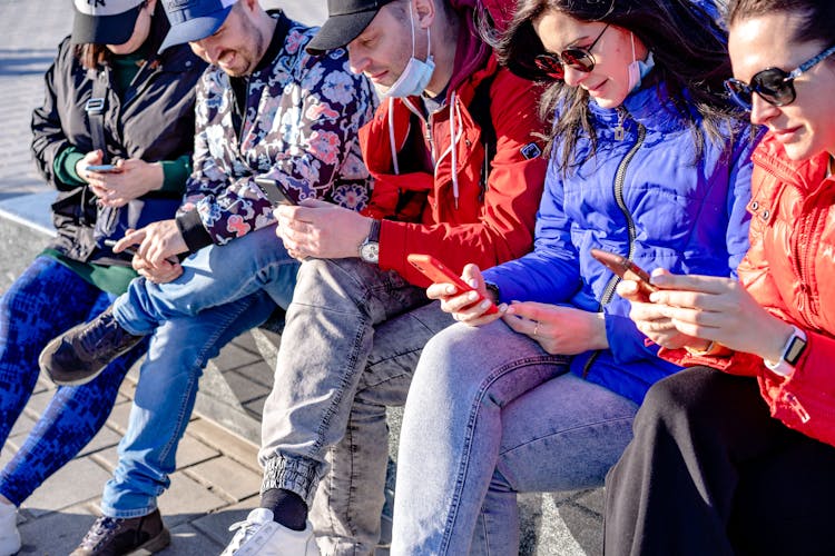 Group Of People Using Smart Phones On City Street