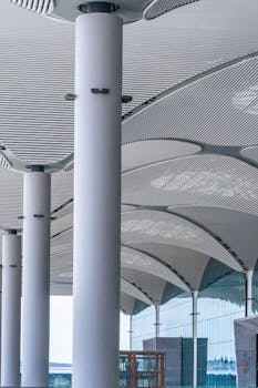 Vertical shot of modern columns and ceiling in a transit hub, showcasing sleek architectural design.