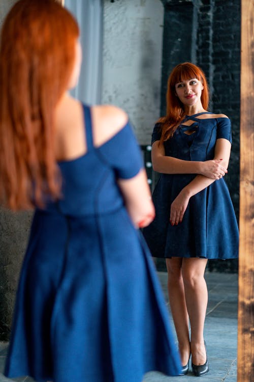 Woman in a Blue Dress Looking at a Mirror