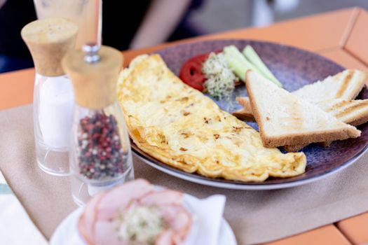 A nicely plated omelette breakfast with toast, cucumbers, and spices. Perfect start to the day.