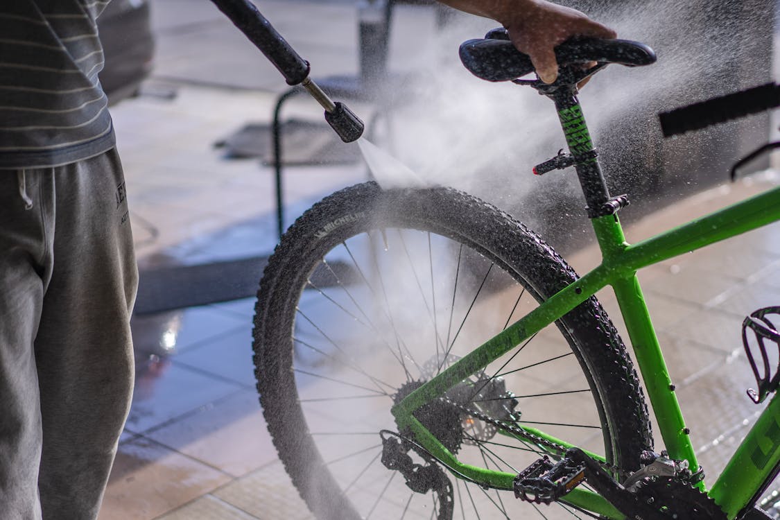Free Man Washing a Bicycle with a Hose Stock Photo