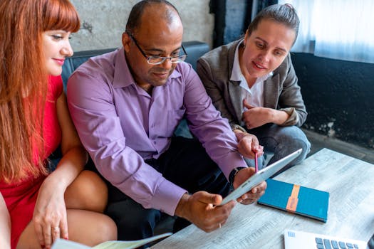 A diverse team collaborating on a project in a modern office setting using a tablet.