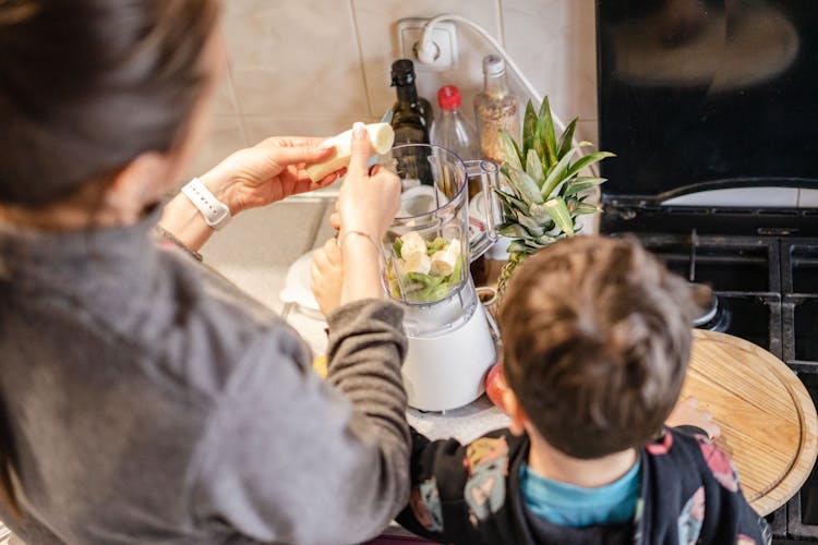 Woman And Child Cooking Fruit Smoothie In Blender