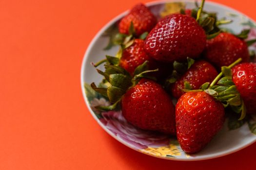 A colorful and vibrant image of ripe strawberries on a floral plate, perfect for healthy food themes.