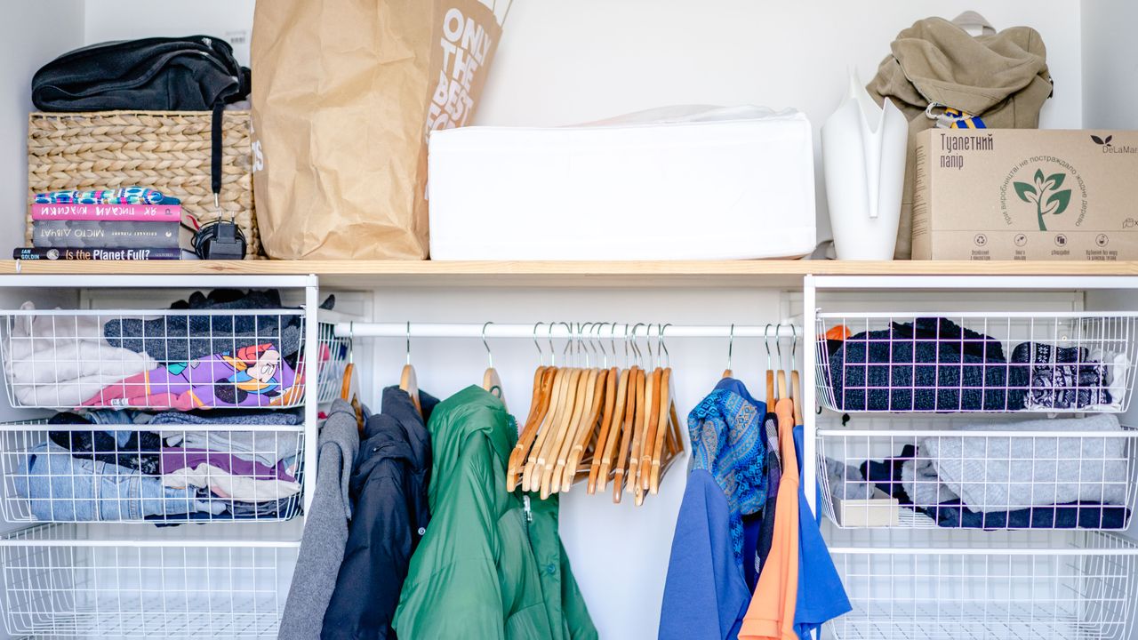 Organized small capsule wardrobe Open wardrobe with organized clothes and baskets for small space capsule wardrobe storage