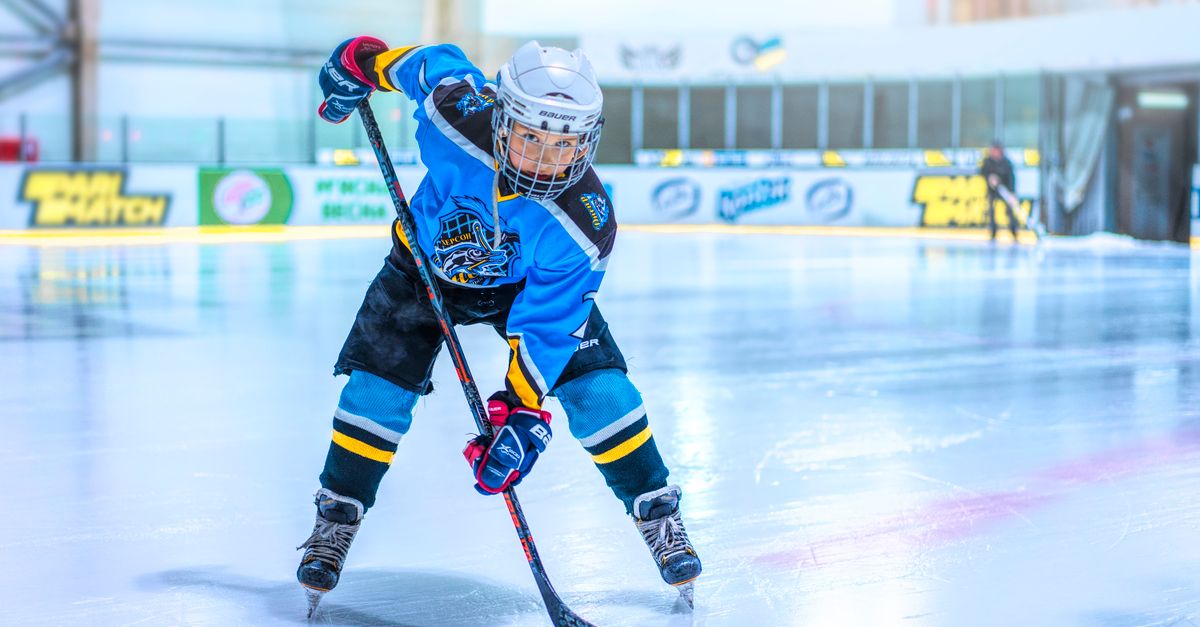 Dynamic shot of a child playing ice hockey indoors, showcasing skill and focus.