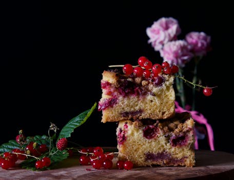 Delicious cake with redcurrants and flowers on a wooden table, perfect for food photography.