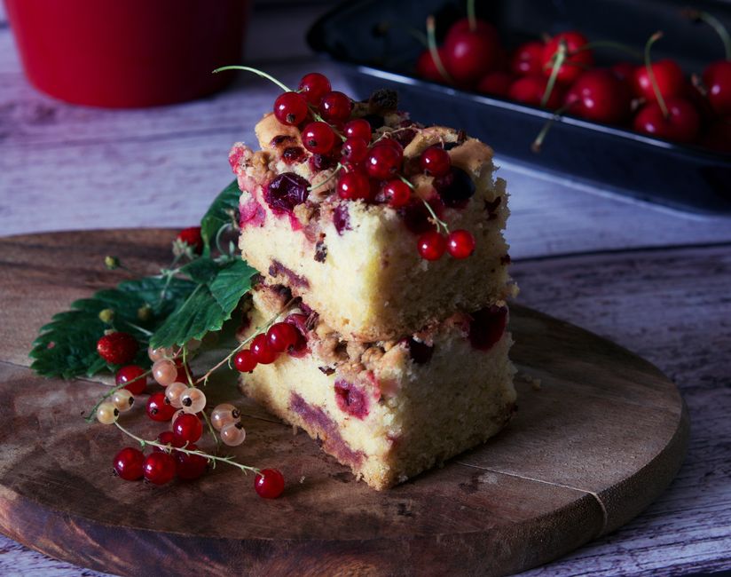 engraved cake slice - A slice of redcurrant-topped cake on a rustic wooden board, perfect for dessert.