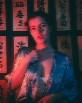 A young woman posing artistically in a silk kimono with soft lighting, creating a dreamy atmosphere.