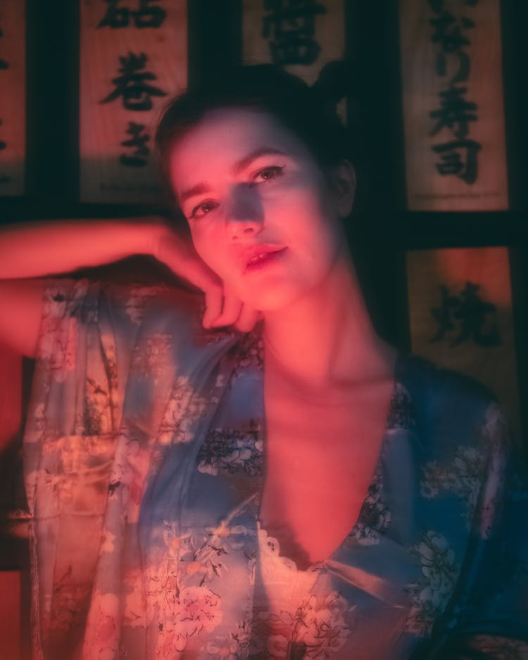 Dark Portrait Of A Woman In Traditional Clothing And Japanese Script On A Wall