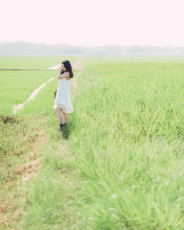 Woman in White Dress Standing on Green Grass Field