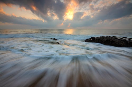 무료 흰색과 노란색 흐린 하늘 아래 물 흐름과 갈색 바위의 시간 경과 사진 스톡 사진