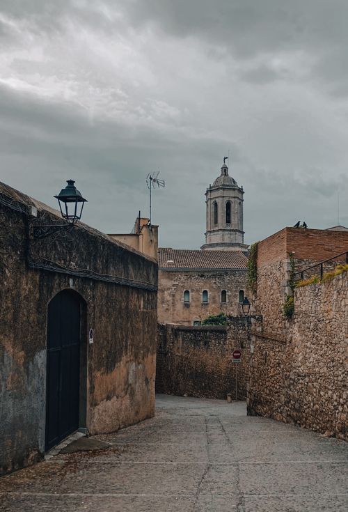 Free A charming alley in Girona, Spain, with a view of the Girona Cathedral under a moody sky. Stock Photo