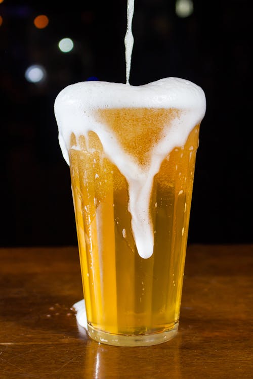 A Close-up Photo of an Overflowing Glass of Beer