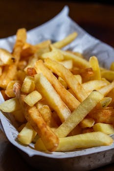 Close-up of golden crispy french fries served in a paper tray, perfect for fast food themes.