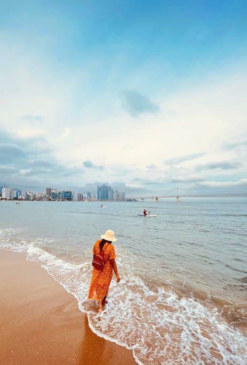 Woman in Yellow Dress Walking on Beach