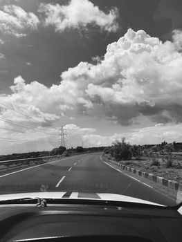 Captivating black and white photo of a road trip through rural India under expansive clouds.