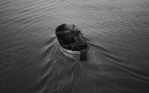 Grayscale Photo of Man in Wooden Boat on Water
