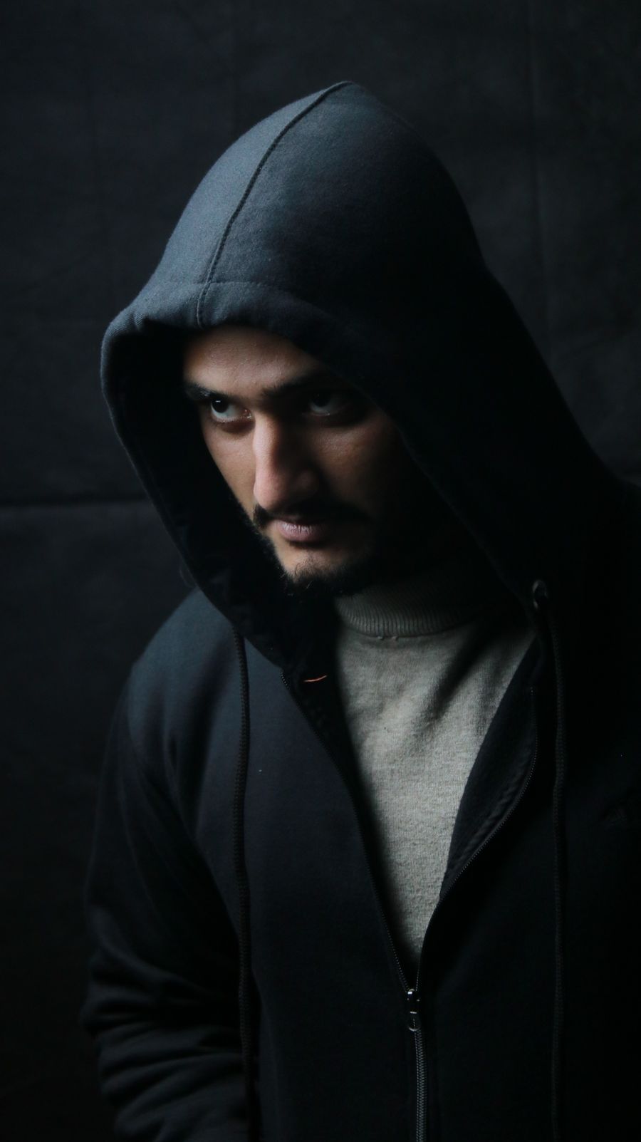 Hombre con hoodie negro y luz dramatica