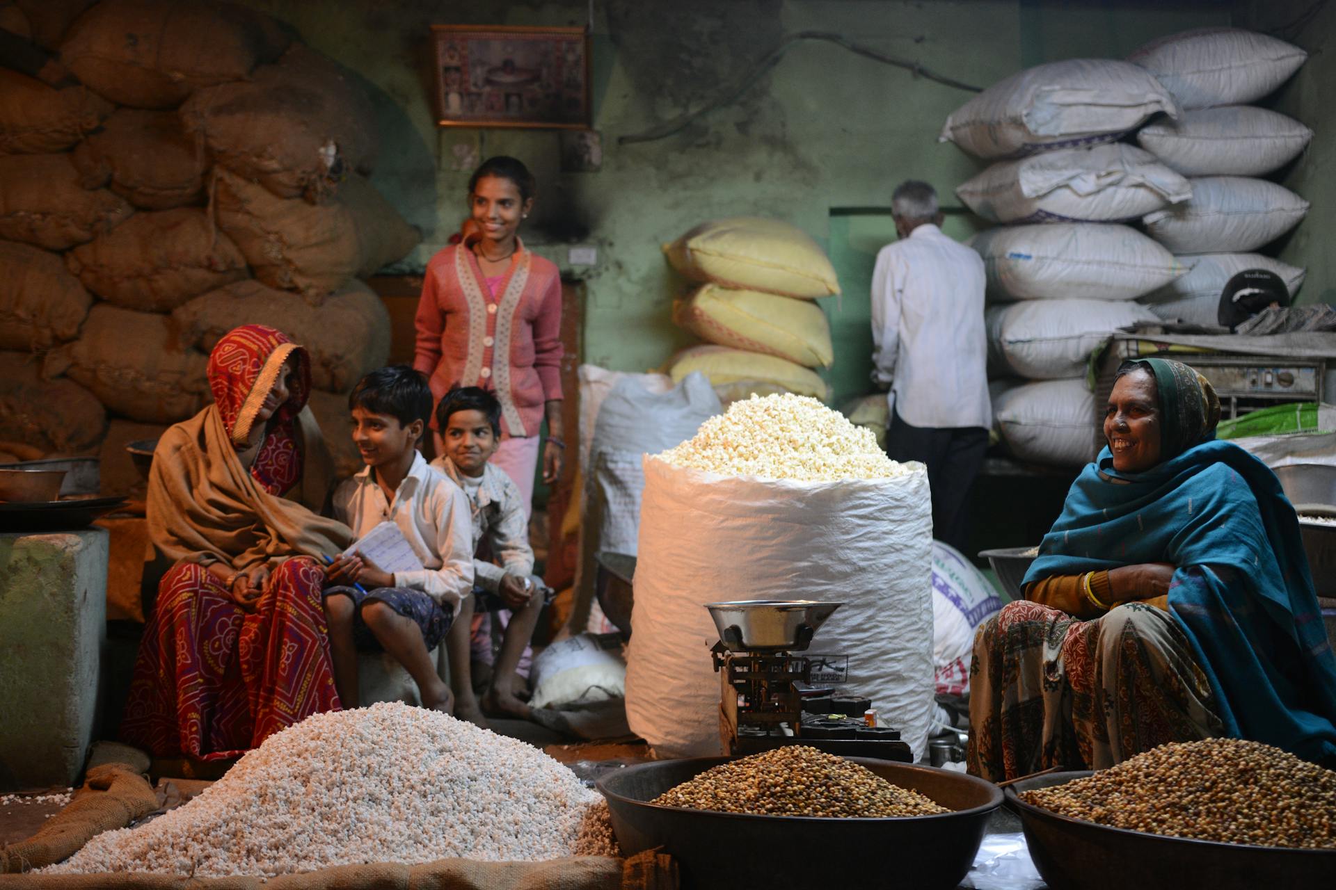 Family vendors selling grains at a busy indoor market in Pushkar, India.