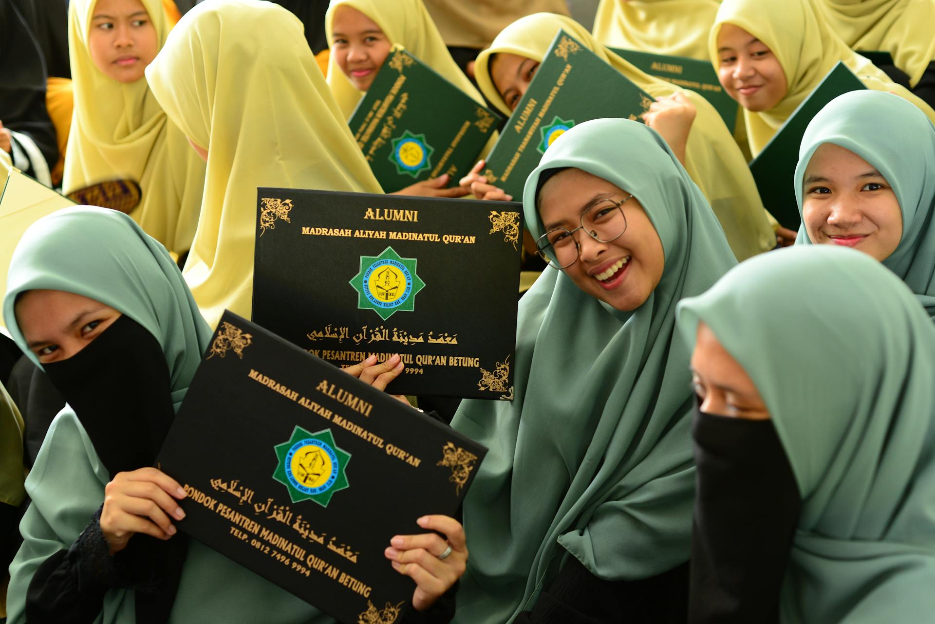 Women Wearing Hijab Holding a Certificate while Posing at the Camera