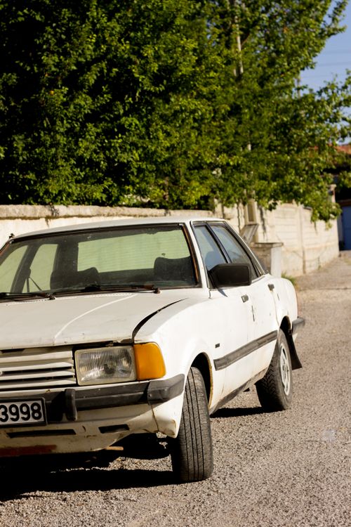 Free A classic vintage car parked on a sunny street, showcasing wear and tear. Stock Photo