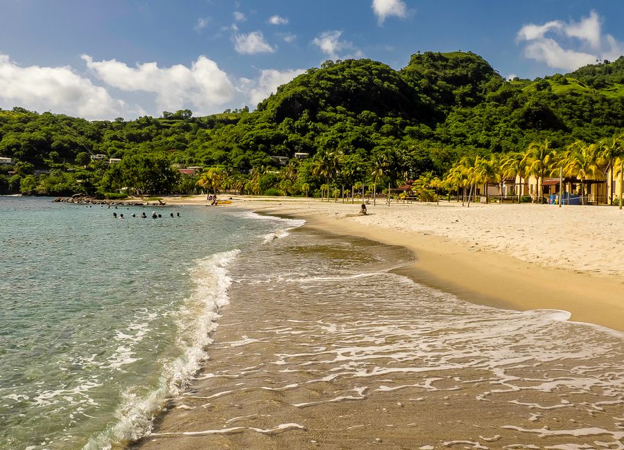 Relaxing beach scene in Buccament, Saint Vincent with villas and lush hills.