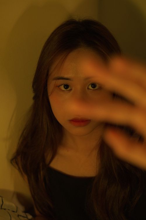 Free Close-up portrait of an Asian woman with hand in foreground, emphasizing expressive eyes. Stock Photo