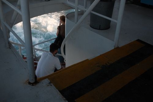 Free Two passengers enjoying the ferry ride, watching the waves from the deck. Stock Photo