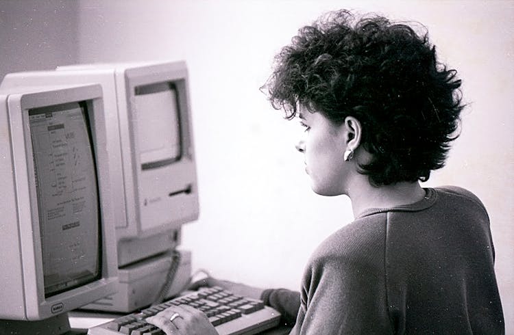 Black And White Photo Of A Woman Using A Vintage Computer