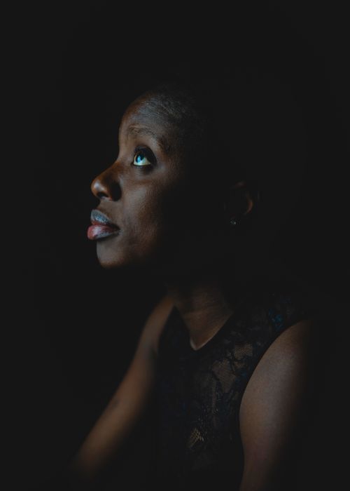 Free Artistic portrait of a woman looking up with a soulful expression, set against a dark background. Stock Photo