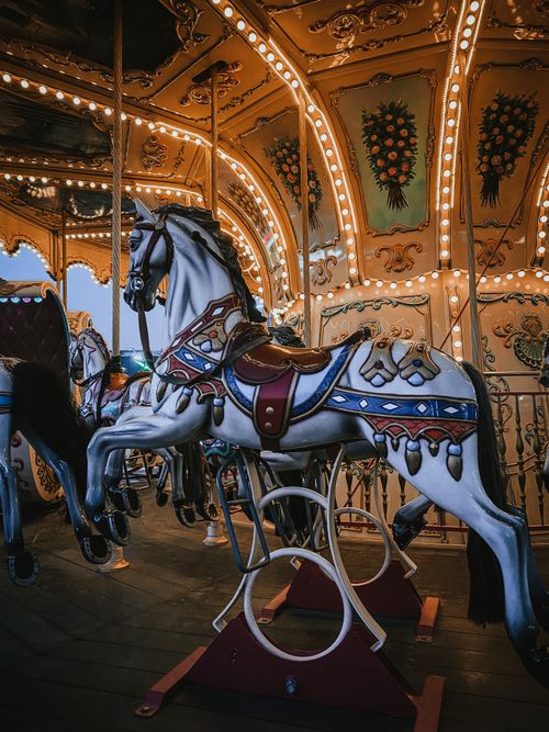 Free Close-up of a decorated carousel horse on a lit vintage amusement ride, evoking nostalgia. Stock Photo