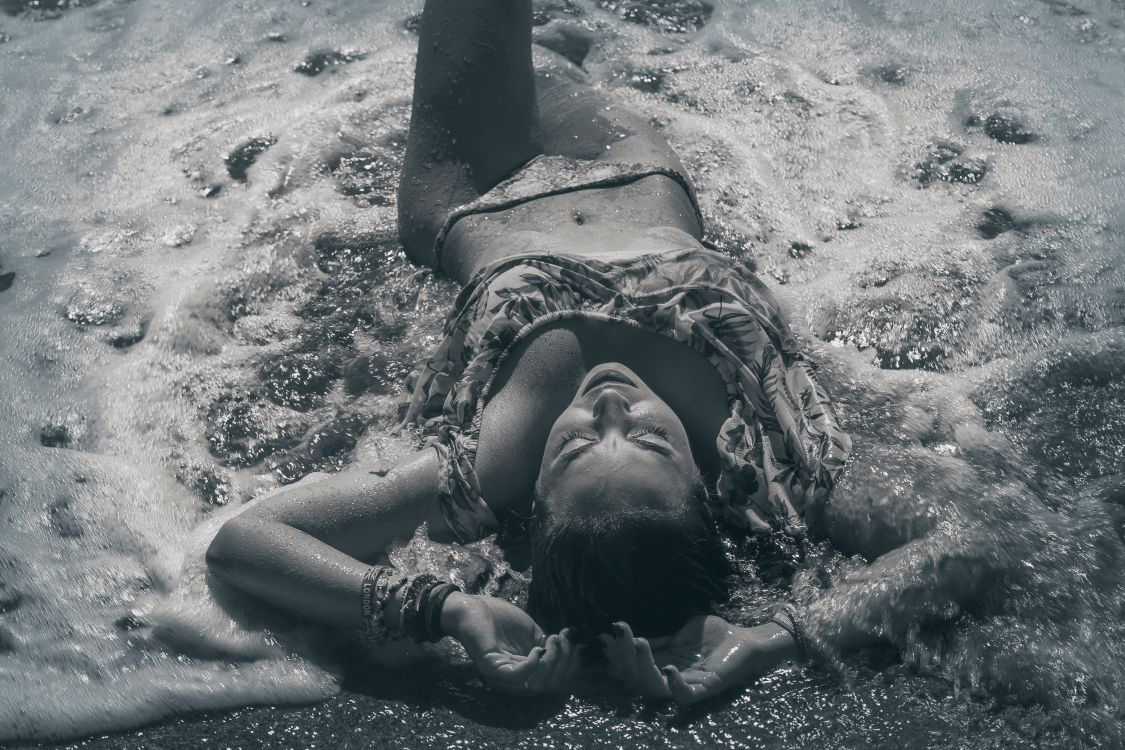 Black and White Photo of a Woman Lying in the Sea · Free Stock Photo
