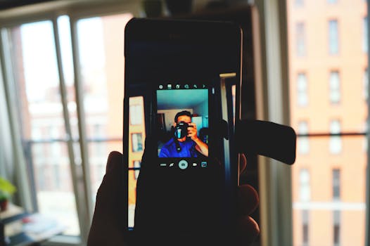A man takes a smartphone selfie capturing his own reflection in an indoor urban setting.