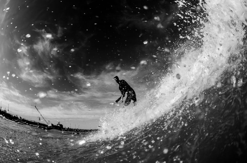 Black and white photo capturing a surfer skillfully riding a wave in Mar del Plata, Argentina.